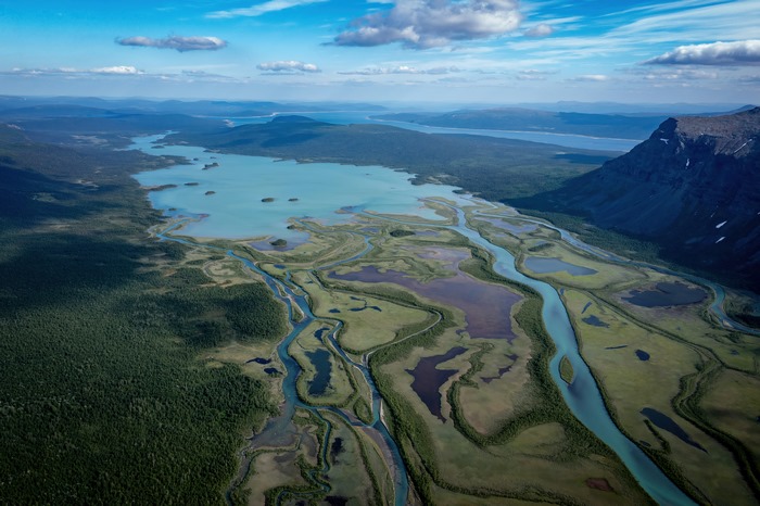 Aerial view of a winding river and lake in a mountainous landscape