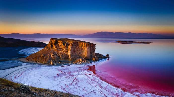 4K Rock Formation by Pink Salt Lake at Sunset