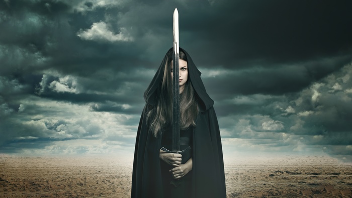 Warrior woman with sword under stormy sky
