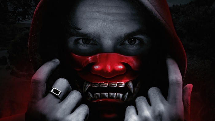 Man wearing a red demon mask and hoodie