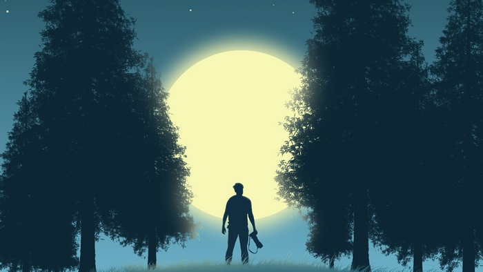 Photographer standing in front of a large moon between trees