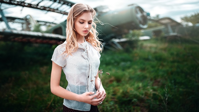 Blonde girl in polka dot shirt near abandoned airplane