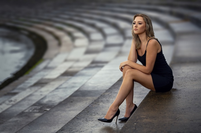 Woman in black dress sitting on outdoor amphitheater steps