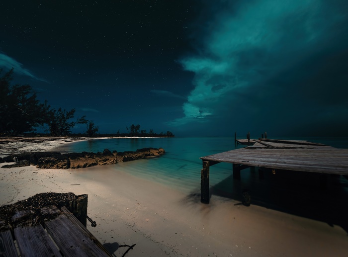 Beach and pier at night under starry sky