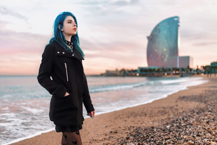 Girl with blue hair on a beach in front of a hotel