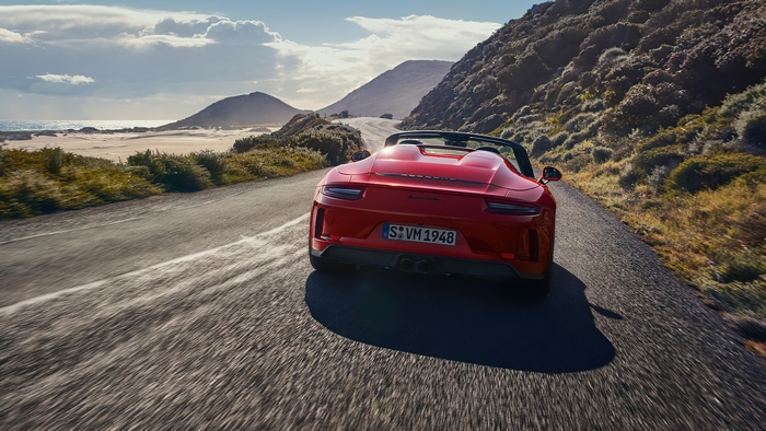 Red Porsche 911 Speedster driving on a coastal road