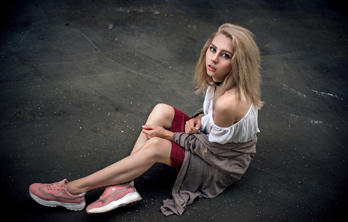 Blonde woman sitting on dark ground