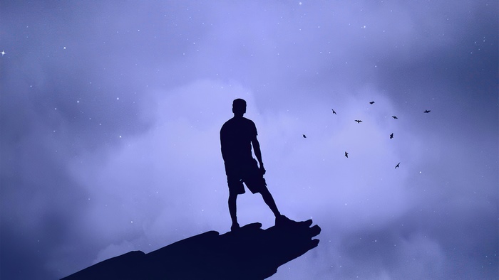 Silhouette of a man standing on a cliff at night