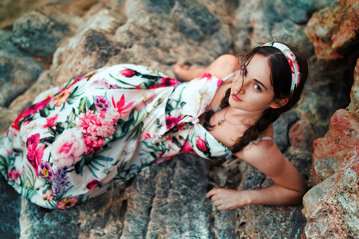 Girl in floral dress lying on rocks
