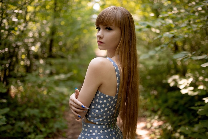 Girl with long hair in a polka dot outfit in a forest