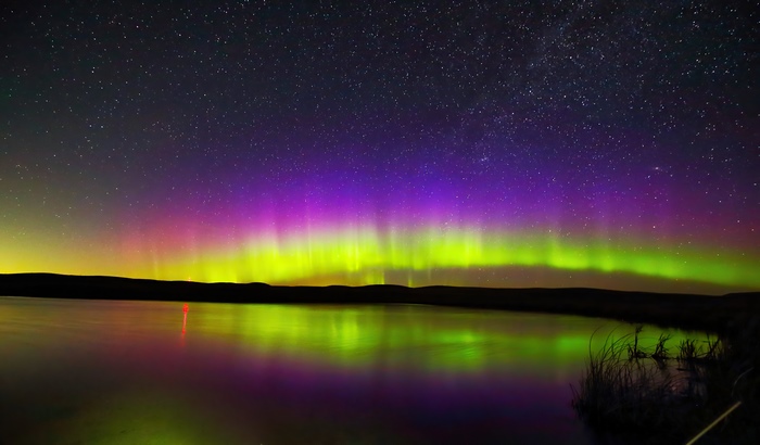 Aurora Borealis over a lake under starry sky