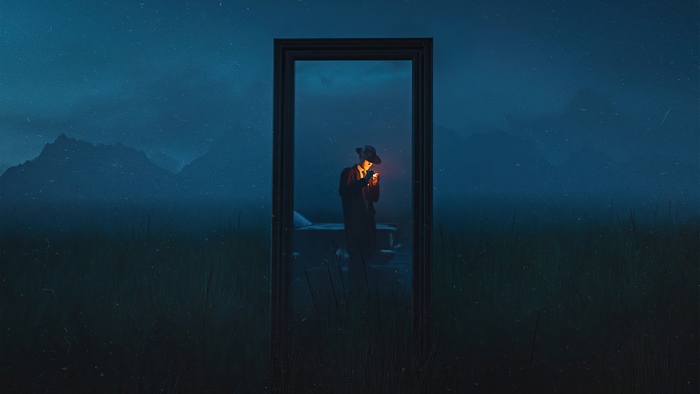 Man in a hat lighting a cigarette in a doorway