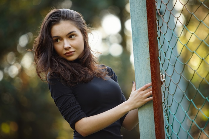 Girl in black dress near fence