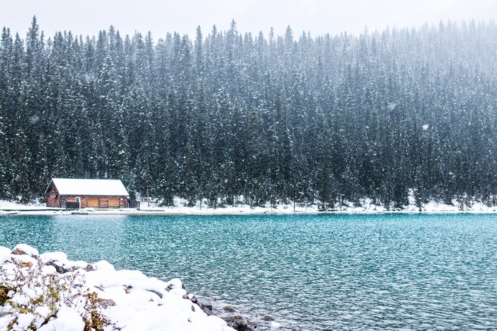 Log cabin on a lake in a snowy forest