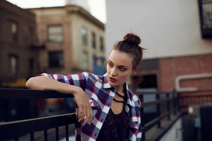 Model in plaid shirt leaning on railing