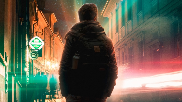 Man with backpack in a city at night