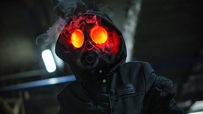 Masked figure in a hoodie with glowing red eyes