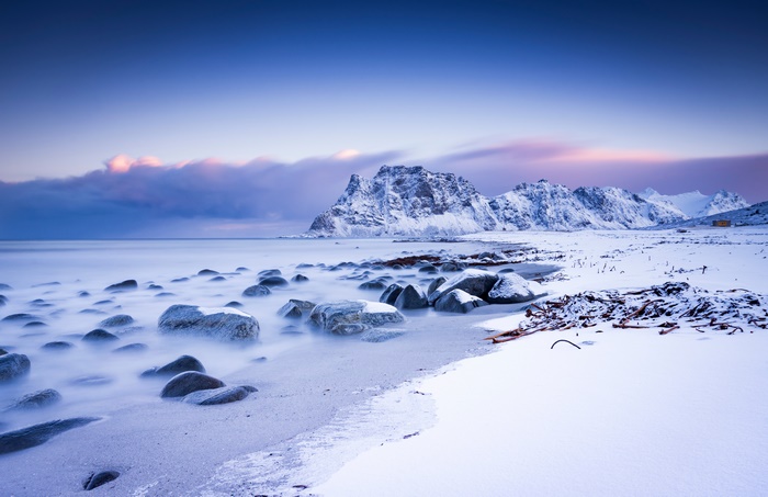 Snowy mountains and rocky shore at dusk