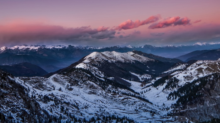 Snow-covered mountains at sunset with pink clouds