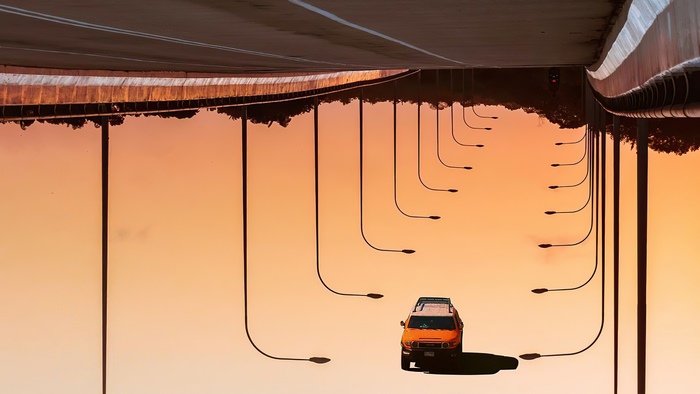 Upside down road with streetlights and orange car
