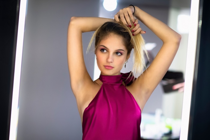 Woman in a purple dress tying her hair