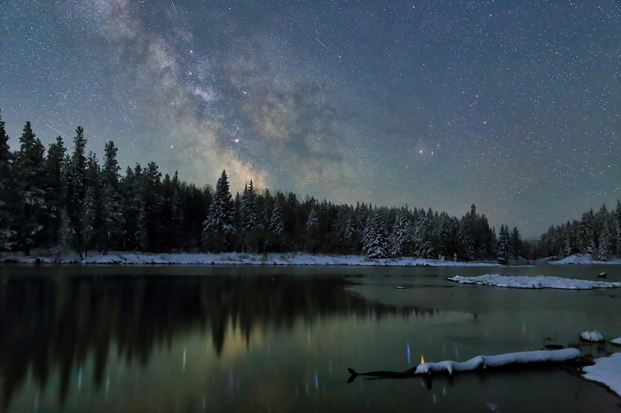 Milky Way over a snowy forest and lake