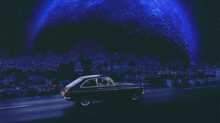 Vintage car driving under a large blue celestial body