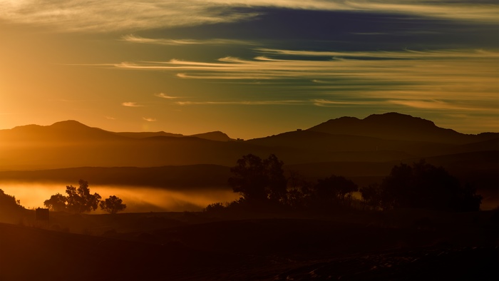 Misty mountains at sunrise with wispy clouds