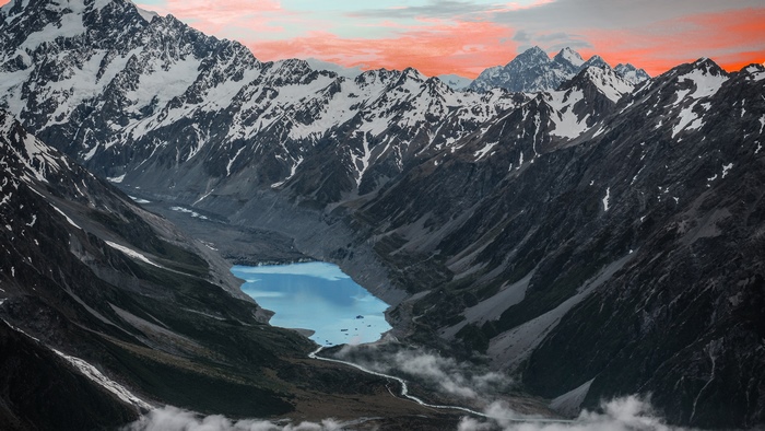 Snow-capped mountains and a blue lake at sunset