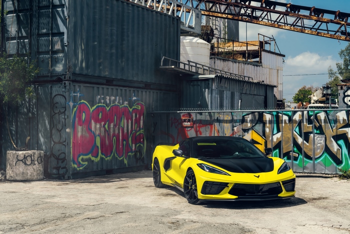 Yellow Chevrolet Corvette C8 parked near graffiti containers