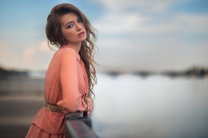 Brunette model in a peach dress by the water