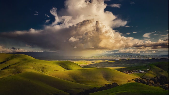 Rolling green hills under a dramatic cloudy sky