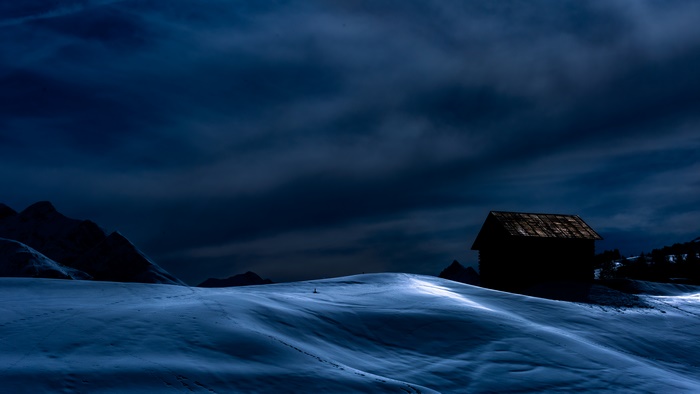 Snowy landscape with a cabin at dusk