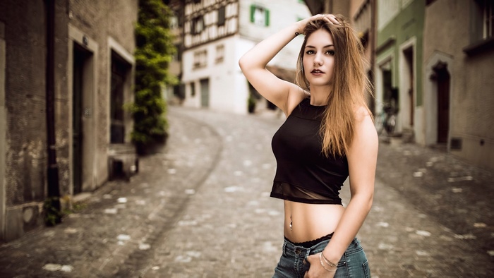 Model in black top and jeans on cobblestone street