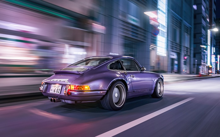 Purple Porsche 911 driving through city at night