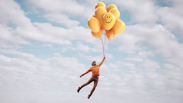 Man flying with yellow balloons in the sky
