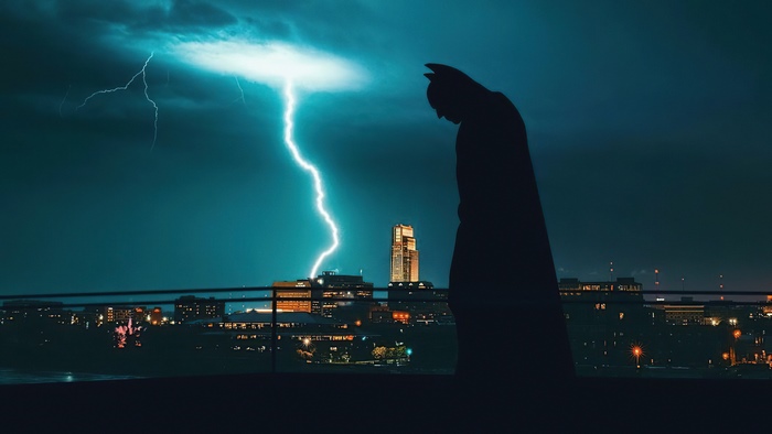 Batman silhouette against lightning over city skyline