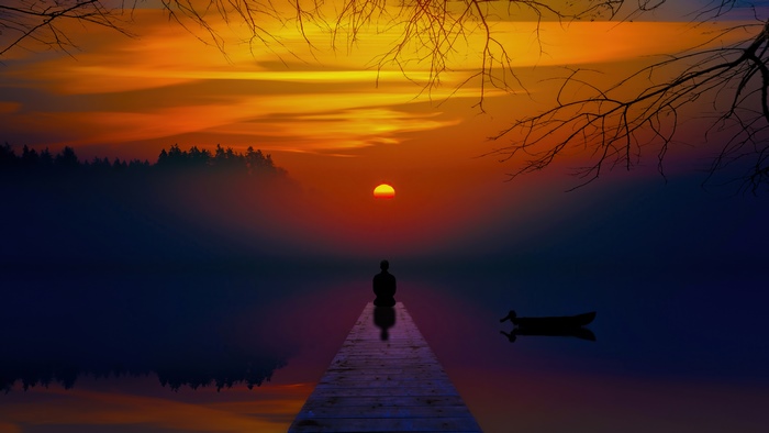 Person meditating on a pier at sunset