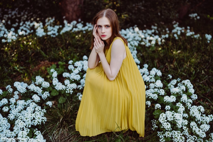 Woman in yellow dress sitting among white flowers