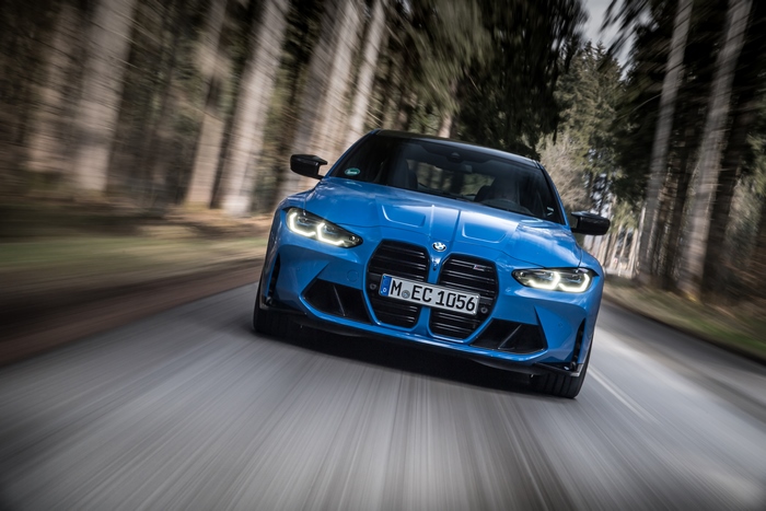 Blue 2021 BMW M4 driving on a forest road