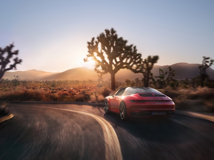 Red Porsche 911 Targa driving in desert at sunset