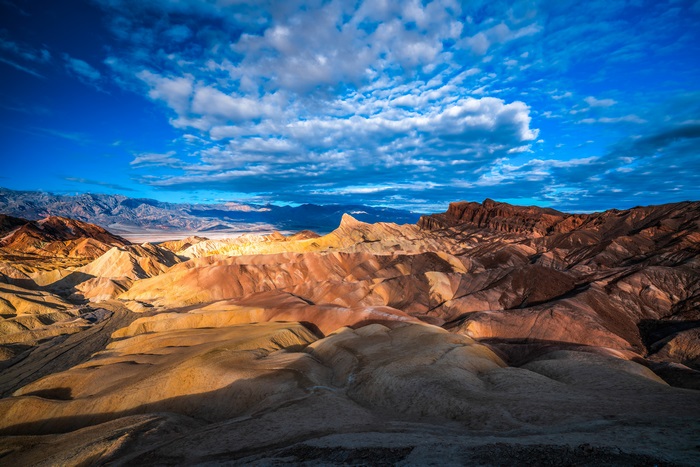 Badlands landscape under a blue sky with clouds