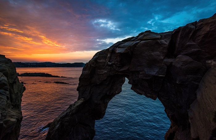 Rock arch over the ocean at sunset