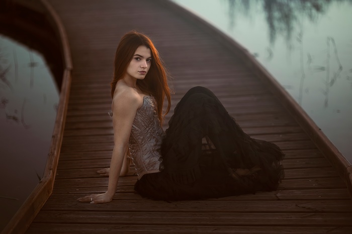 Girl in corset and skirt on wooden pier