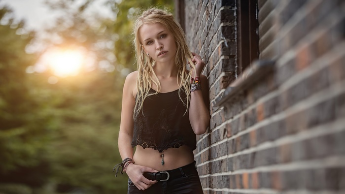 Young woman with dreadlocks leaning against a brick wall