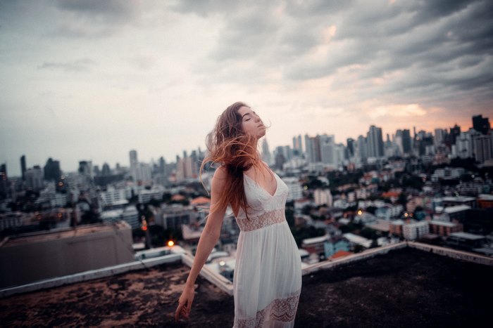 Woman in white dress on rooftop overlooking city