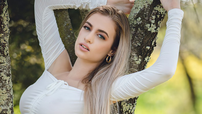Model in white dress posing by tree