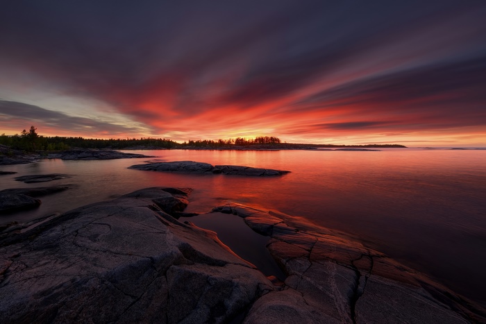 Dramatic sunset over rocky shore and calm water
