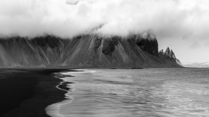 Black and white mountain landscape with ocean waves