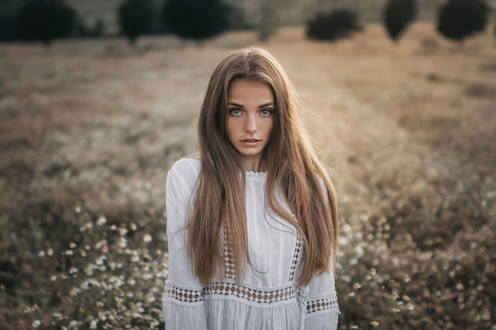 Young blonde girl in white dress in field